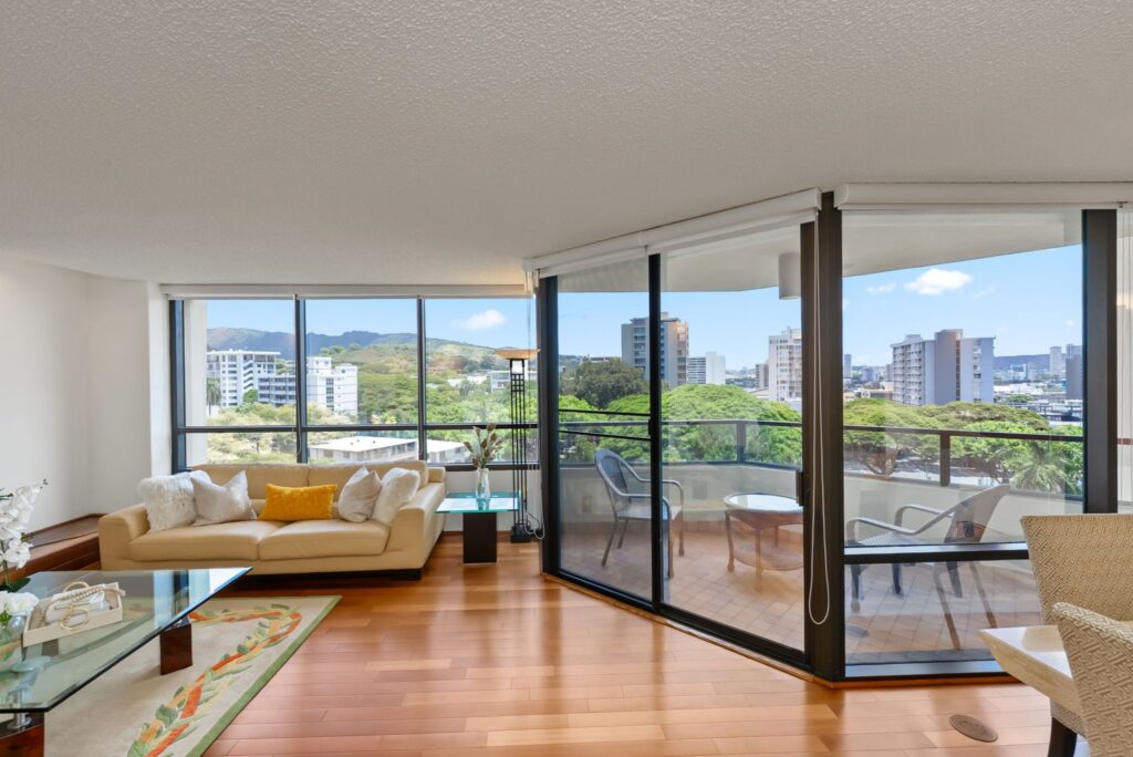 Bright living room with floor-to-ceiling windows and panoramic treetop and mountain views.