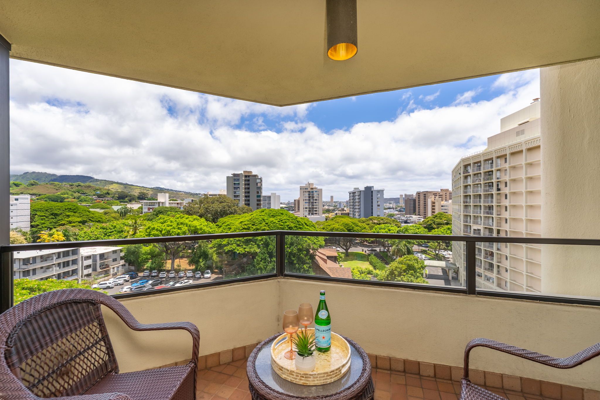 Covered lanai overlooking lush treetops, mountains, and city views.