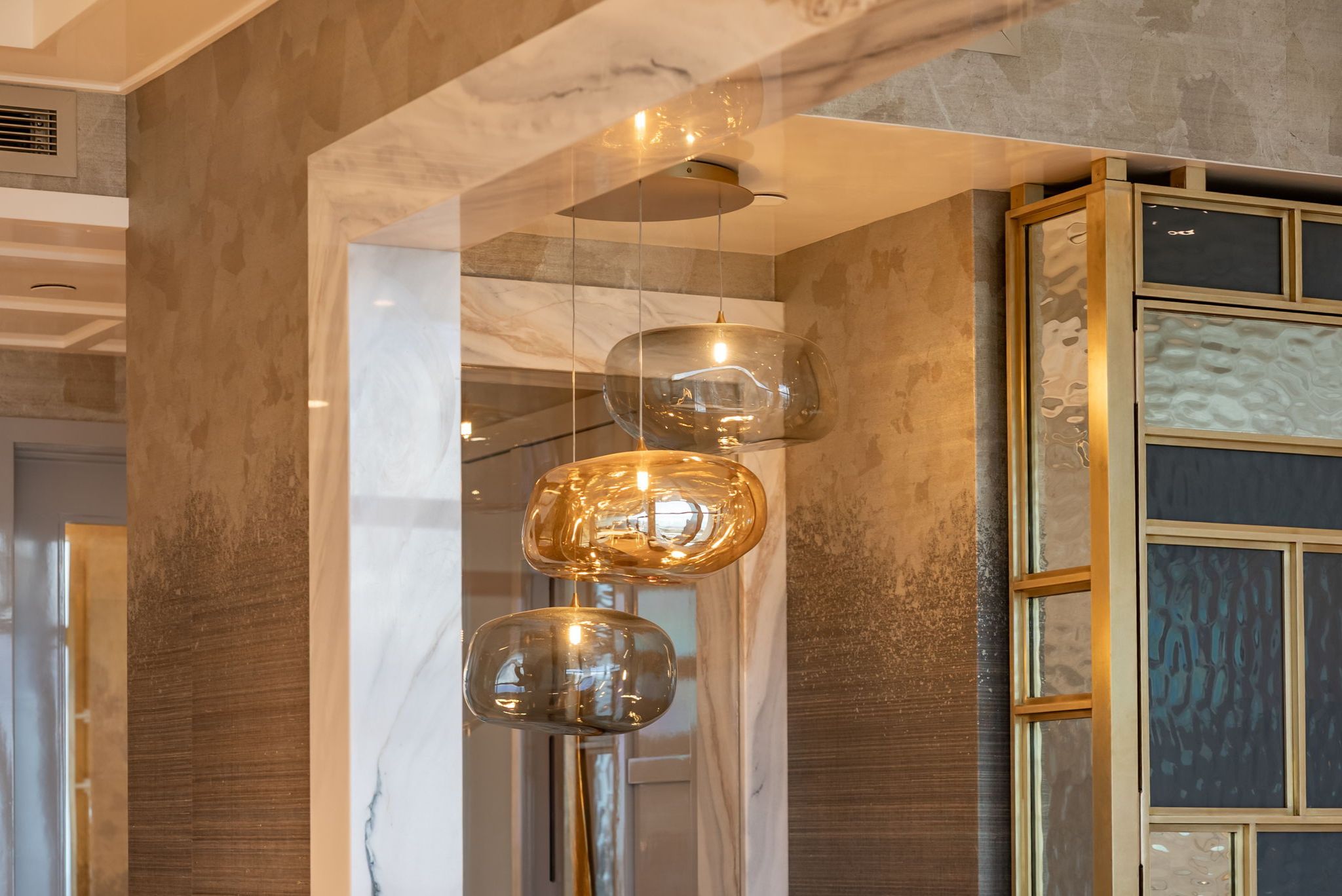 Custom hand-blown chandelier and marble-framed architectural opening in Grand Penthouse 4003