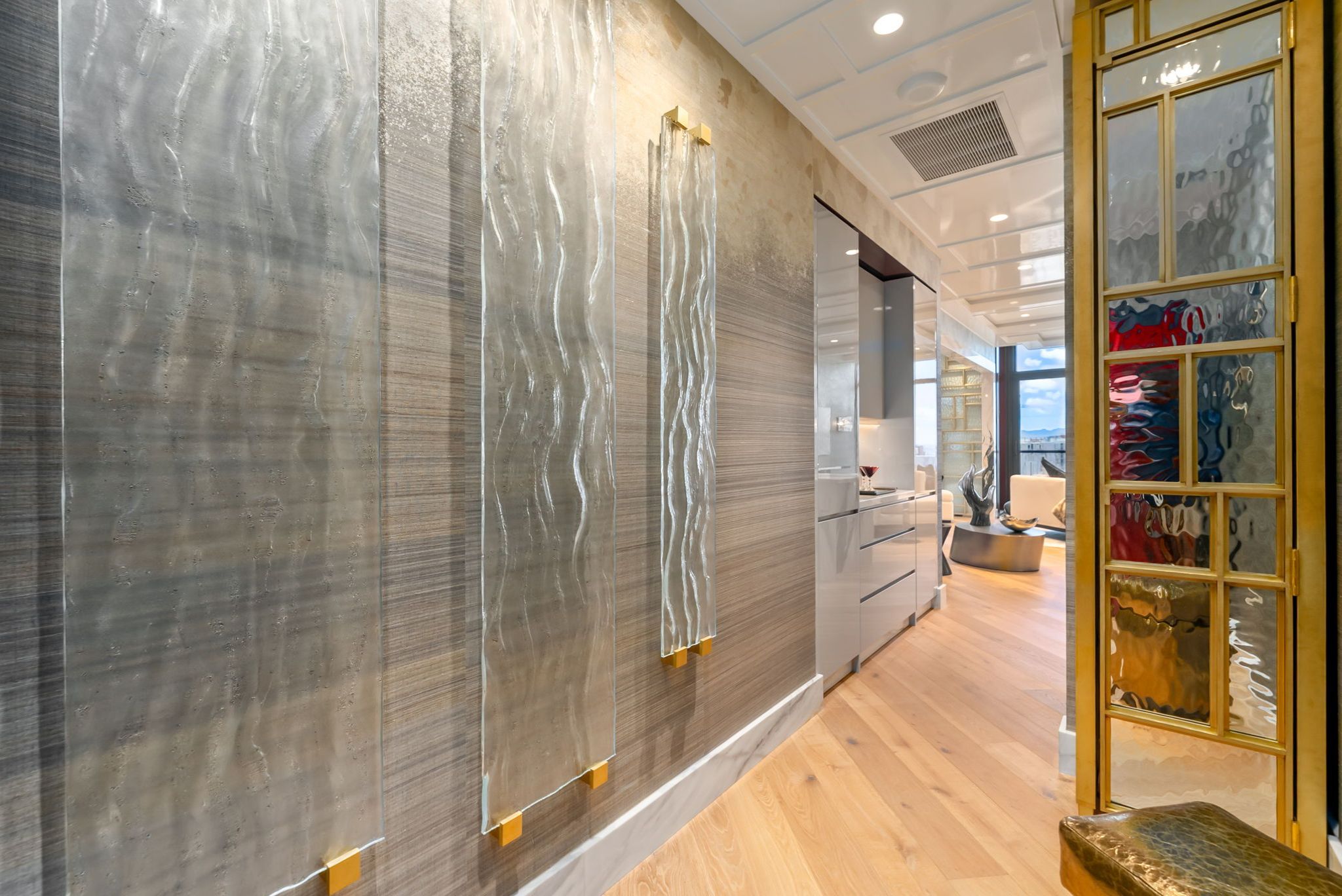 Grand Penthouse 4003 entry showcasing textured wallcoverings, custom lighting and brass-framed glass details